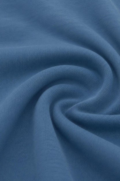 A close-up of draped blue fabric with a fine ribbed texture, arranged in a spiral pattern..