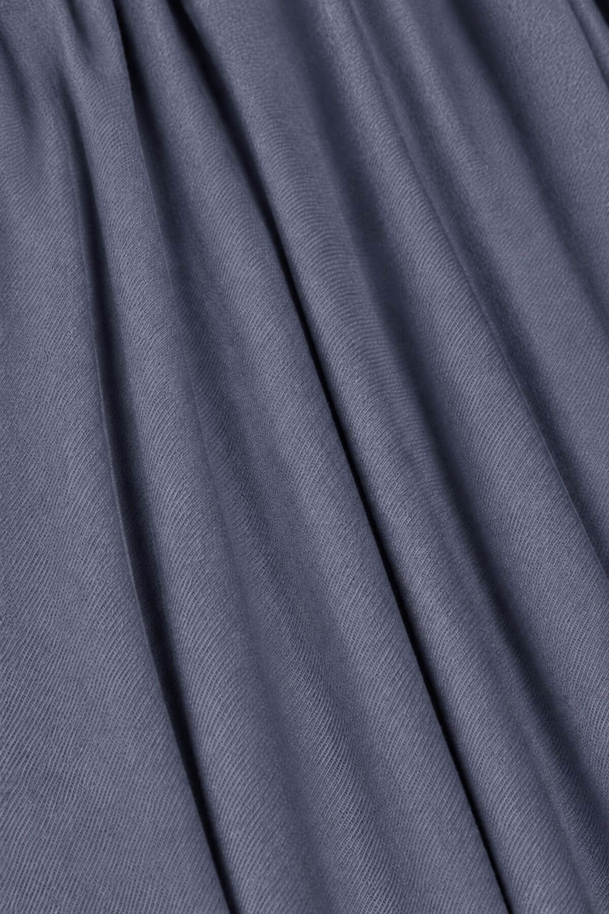 A close-up of draped slate blue fabric with soft folds and a fine woven texture.