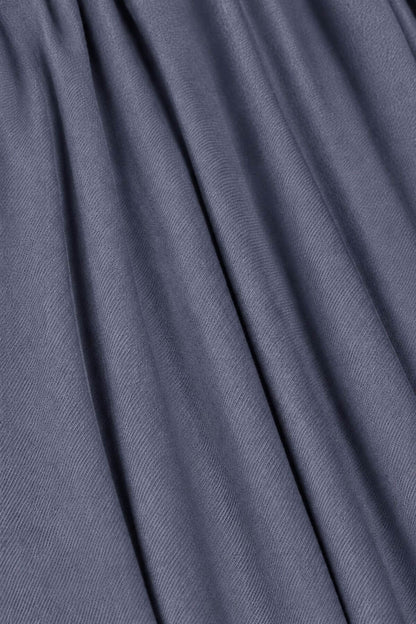 A close-up of draped slate blue fabric with soft folds and a fine woven texture.