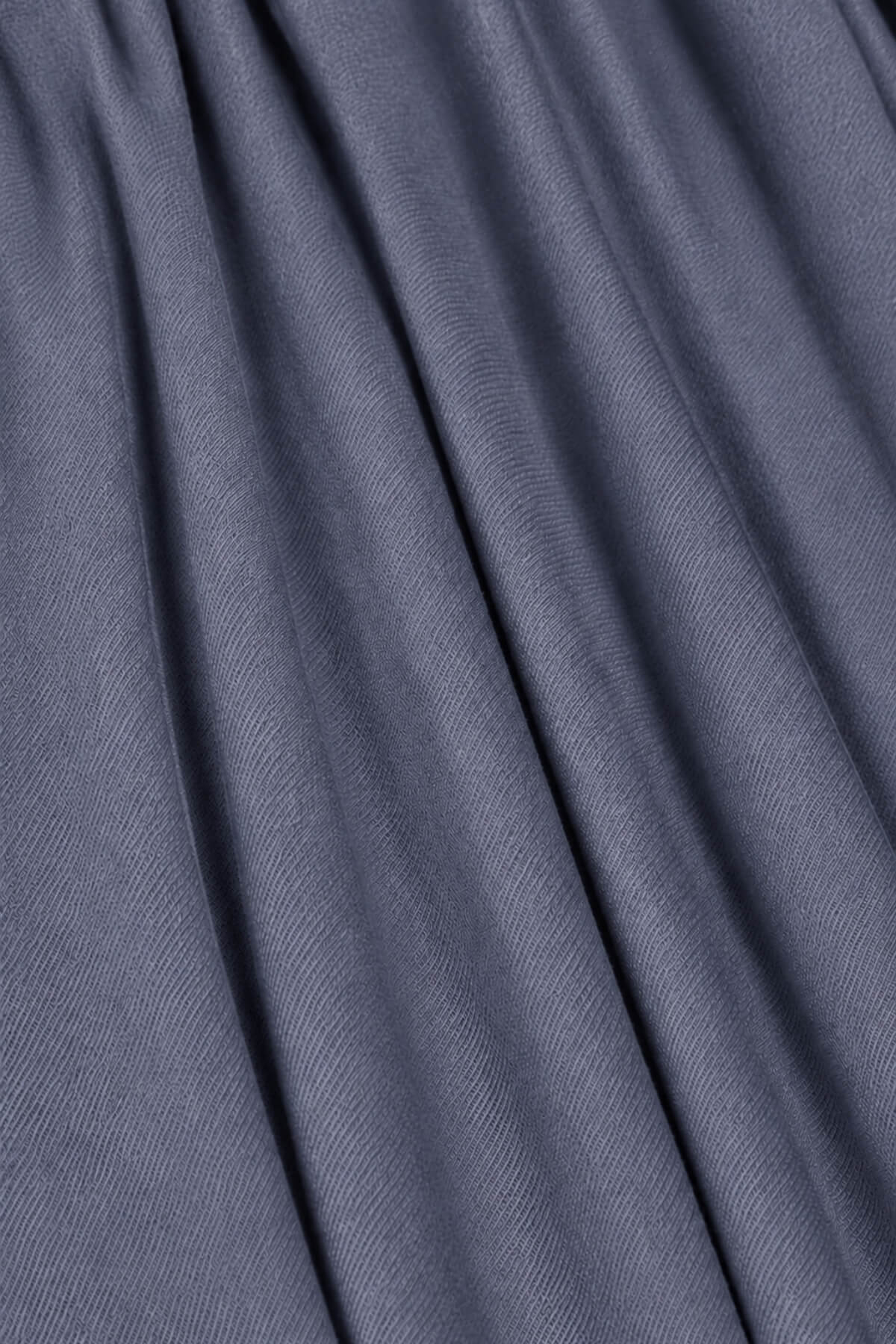 A close-up of draped slate blue-gray fabric with soft folds and a fine woven texture.