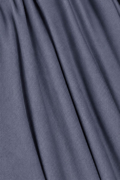 A close-up of draped slate blue-gray fabric with soft folds and a fine woven texture.