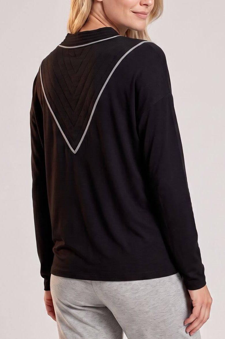 A woman shown from the back wearing a black long-sleeve top with a silver geometric line detail on the back and light gray sweatpants, against a light gray studio background..