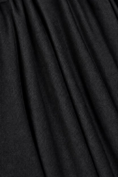 A close-up of black pleated fabric with soft vertical folds and a fine textured weave.