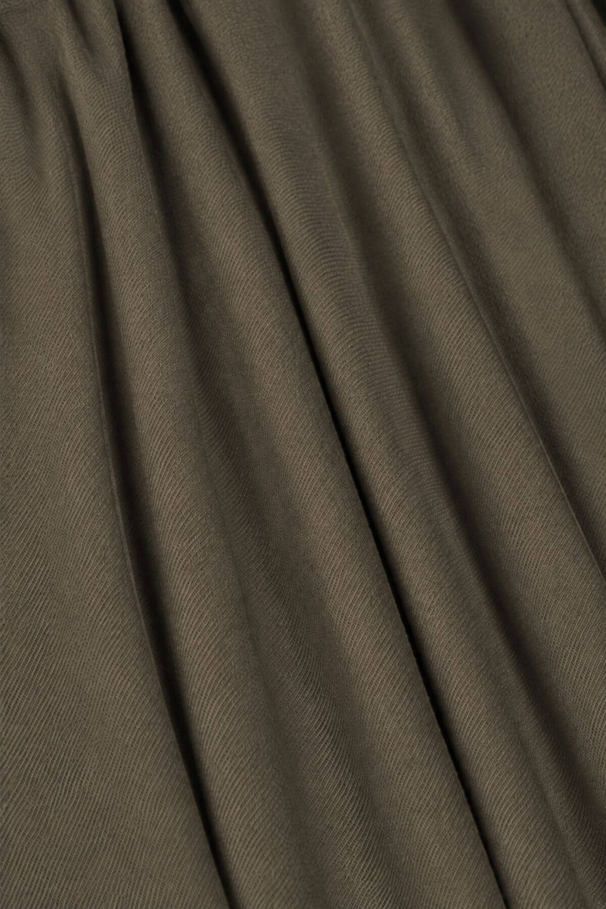 A close-up of draped fabric in a muted taupe-brown color, showing the texture and folds.