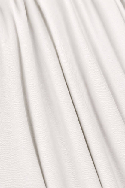 A close-up of draped off-white fabric with soft vertical folds and a fine woven texture.