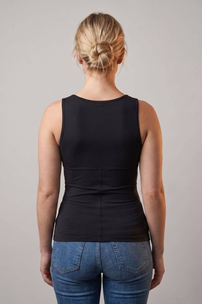 A woman viewed from the back wearing a black sleeveless tank top and blue jeans against a plain light gray studio background.