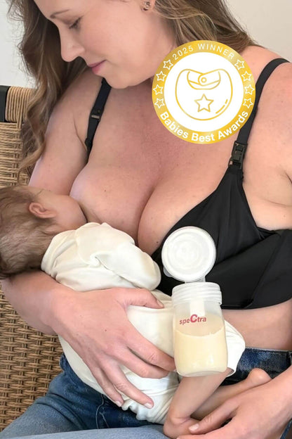 Woman breastfeeding a baby while wearing a hands free pumping and nursing bra that is holding a full bottle  of expressed breastmilk with a visible 2025 babies best award badge in the corner.