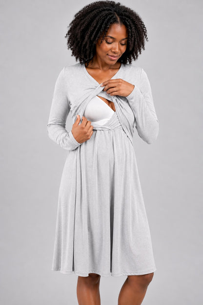 A woman modeling a light gray long-sleeve maternity dress with a front split opening, shown against a solid gray studio background