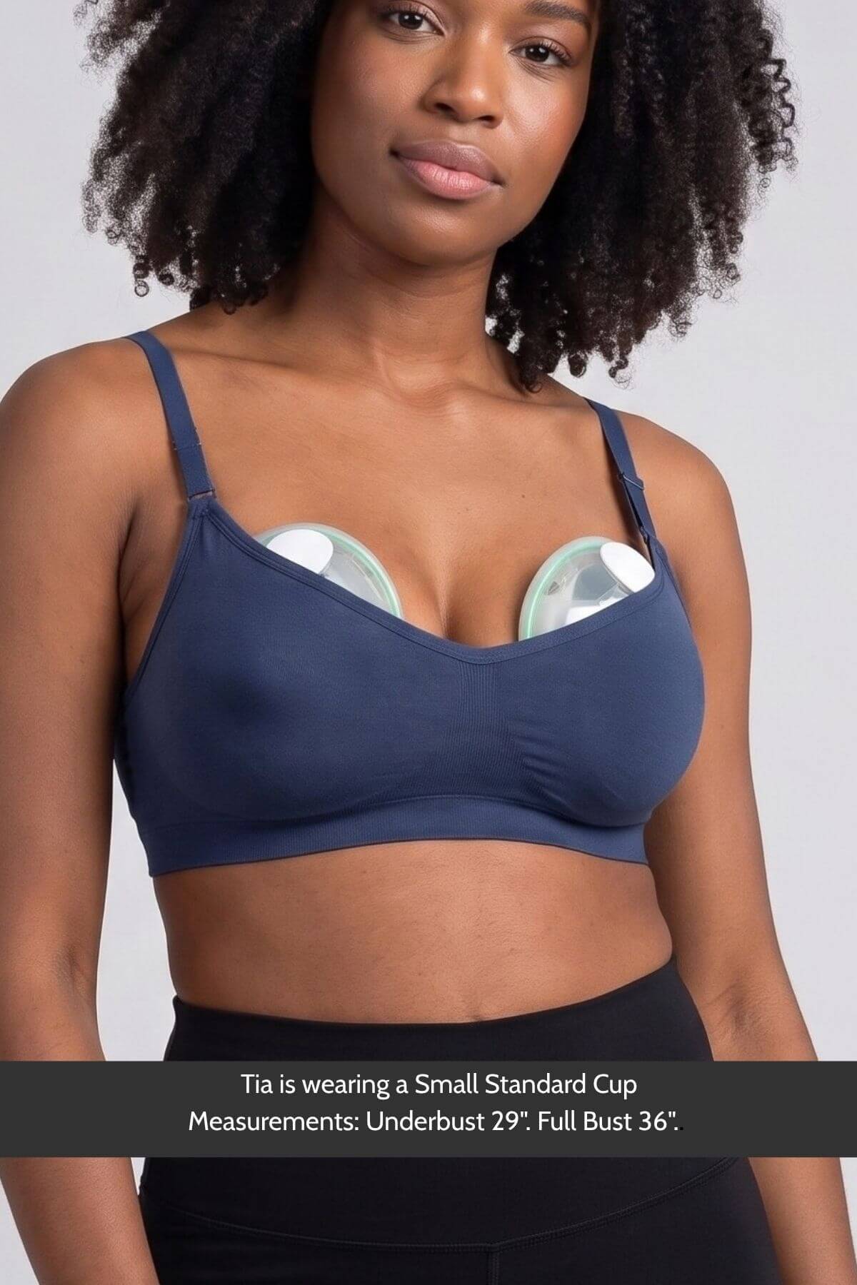 A woman wearing the Stages Nursing Bra, Maternity Bra, Wearable Pump Bra and Everyday Bra all-in-one in indigo with Elvie Stride wearable pumps inserted, shown from the chest up against a light gray background. A text banner at the bottom reads: &