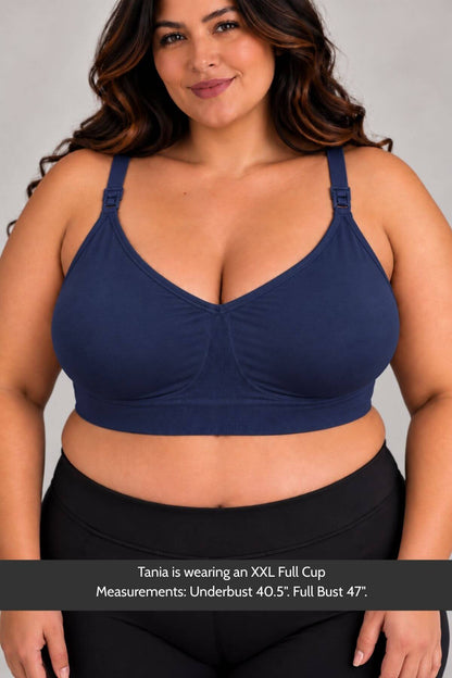 A plus-size woman wearing the Stages Nursing Bra, Maternity Bra, Wearable Pump Bra and Everyday Bra all-in-one in indigo and black leggings, shown against a light gray studio background with a text banner at the bottom detailing measurements.