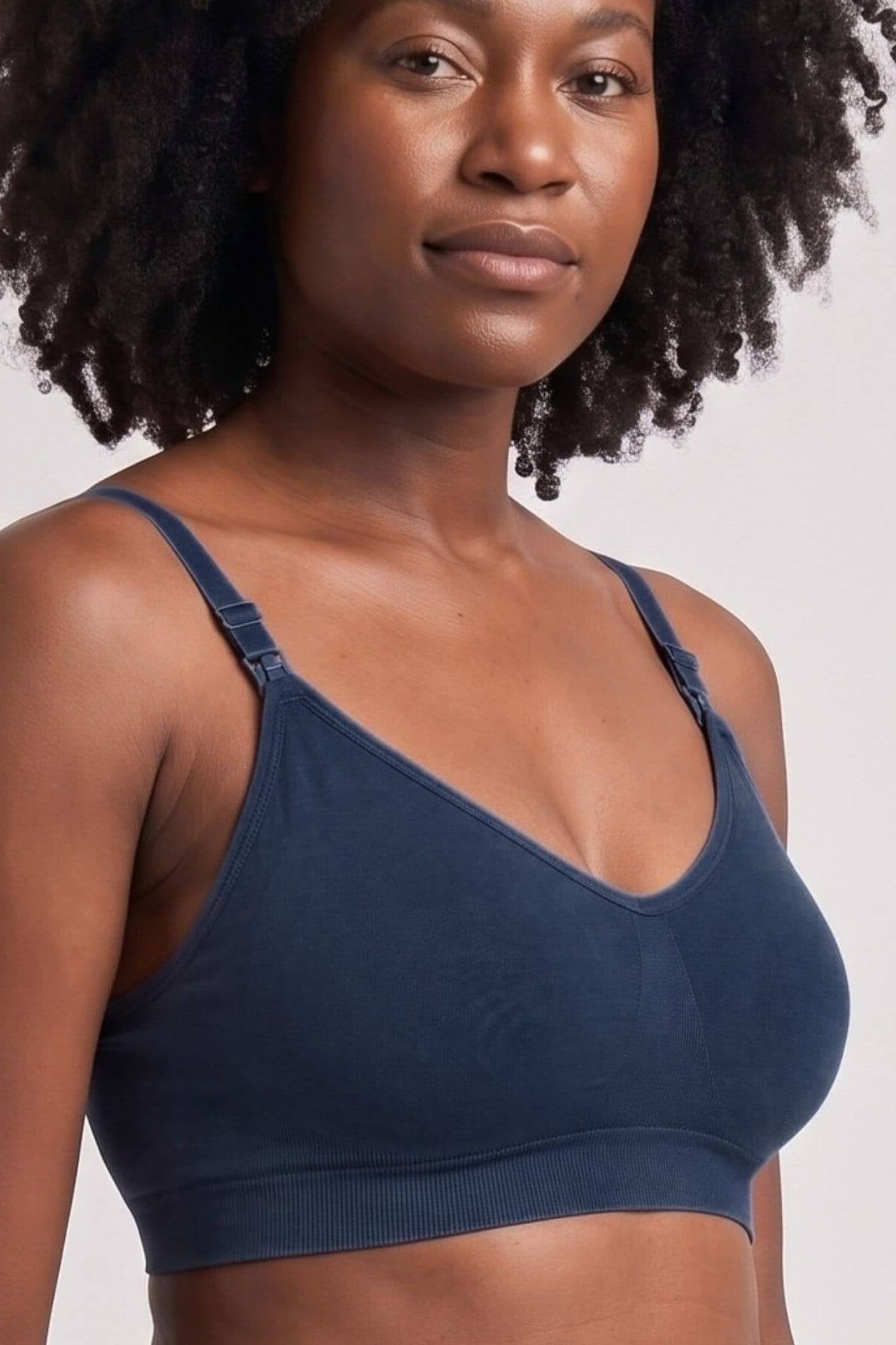 A close-up shot of a woman wearing the Stages Nursing Bra, Maternity Bra, Wearable Pump Bra and Everyday Bra all-in-one in indigo against a light gray background.