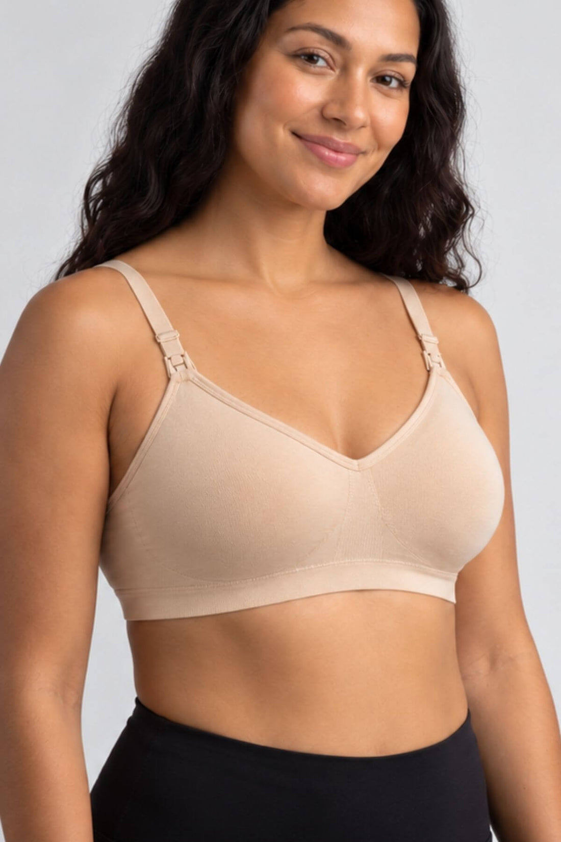 A woman wearing the Stages Maternity, Nursing, Wearable Pump &amp; Everyday Bra in Sunkissed Rose with front adjustable shoulder straps, shown from the chest up against a light gray studio background.