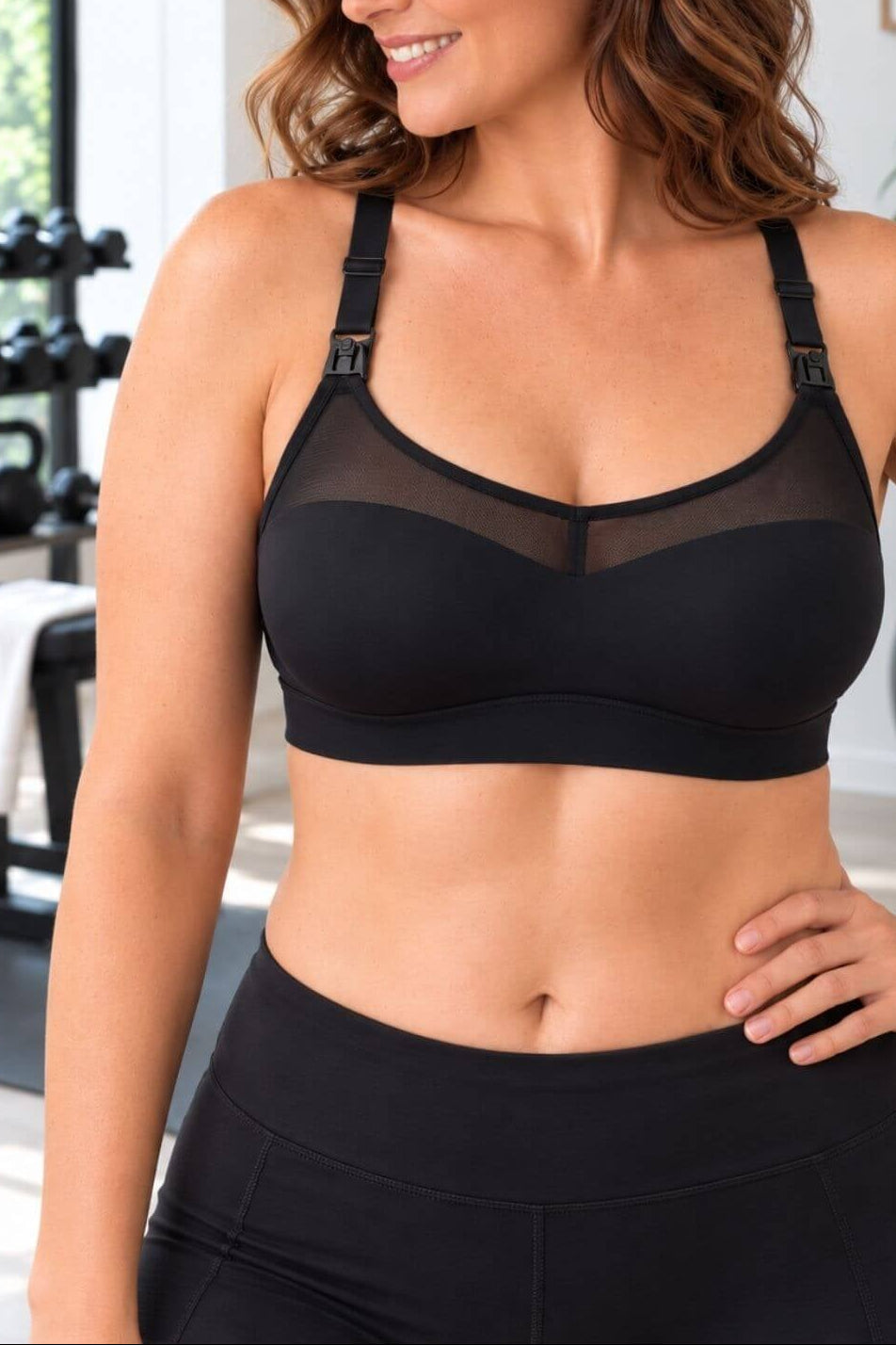 A woman wearing athe Stages sweetheart mesh racerback style nursing bra and black leggings in a bright gym setting.