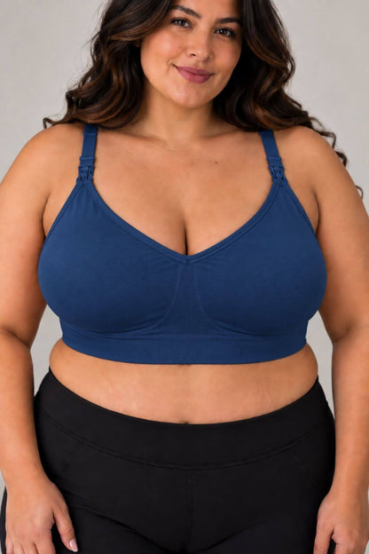 A woman wearing the supermom silhouette nursing and hands free pumping bra and black high-waisted leggings, shown from the chest down against a plain light gray studio background.