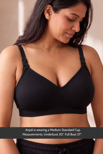 A woman wearing a  simple wishes silhouette nursing &amp; hands free pumping bra with front adjustable shoulder straps, shown from the chest up against a soft beige background. A text banner at the bottom reads: &