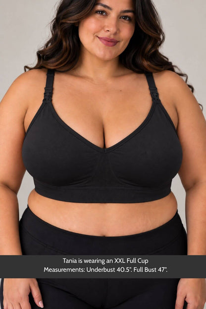 A plus-size woman wearing simple wishes silhouette nursing &amp; hands free pumping bra and black bottoms, shown from the chest down against a light gray studio background. A text banner at the bottom reads: &