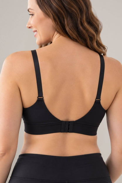 A woman shown from the back wearing a the Simple Wishes V mesh tank style nursing and hands free pumping sports bra and matching black bottoms against a plain light gray studio background.