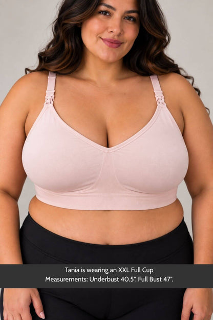 A plus-size woman wearing  a simple wishes supermom silhouette nursing bra and hands free pumping bra in ballet slipper pink, with text at the bottom stating measurements for an XXL Full Cup.