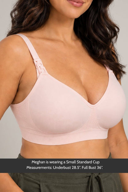 A woman wearing a simple wishes supermom silhouette nursing bra and hands free pumping bra in ballet slipper pink with afront djustable shoulder straps and a wide underband, shown from the chest down against a plain light gray background. A text banner at the bottom provides sizing information.