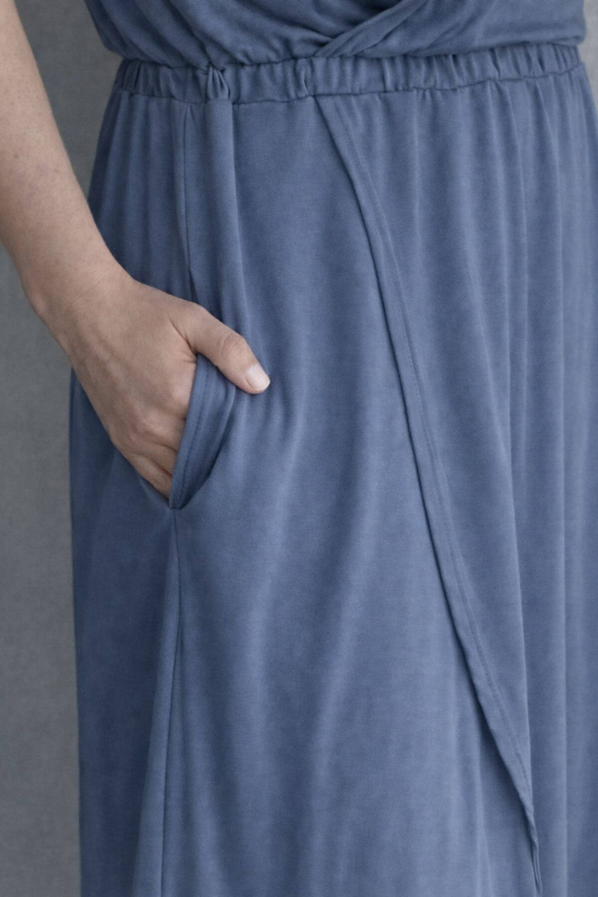 Close up skirt view of a woman wearing a gray blue nursing dress against a light gray background