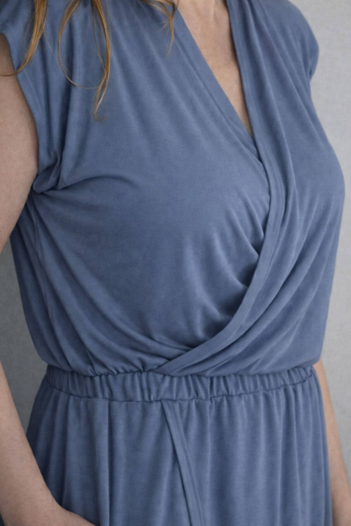 Close up top view of a woman wearing a gray blue nursing dress against a light gray background