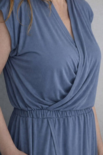 Close up top view of a woman wearing a gray blue nursing dress against a light gray background