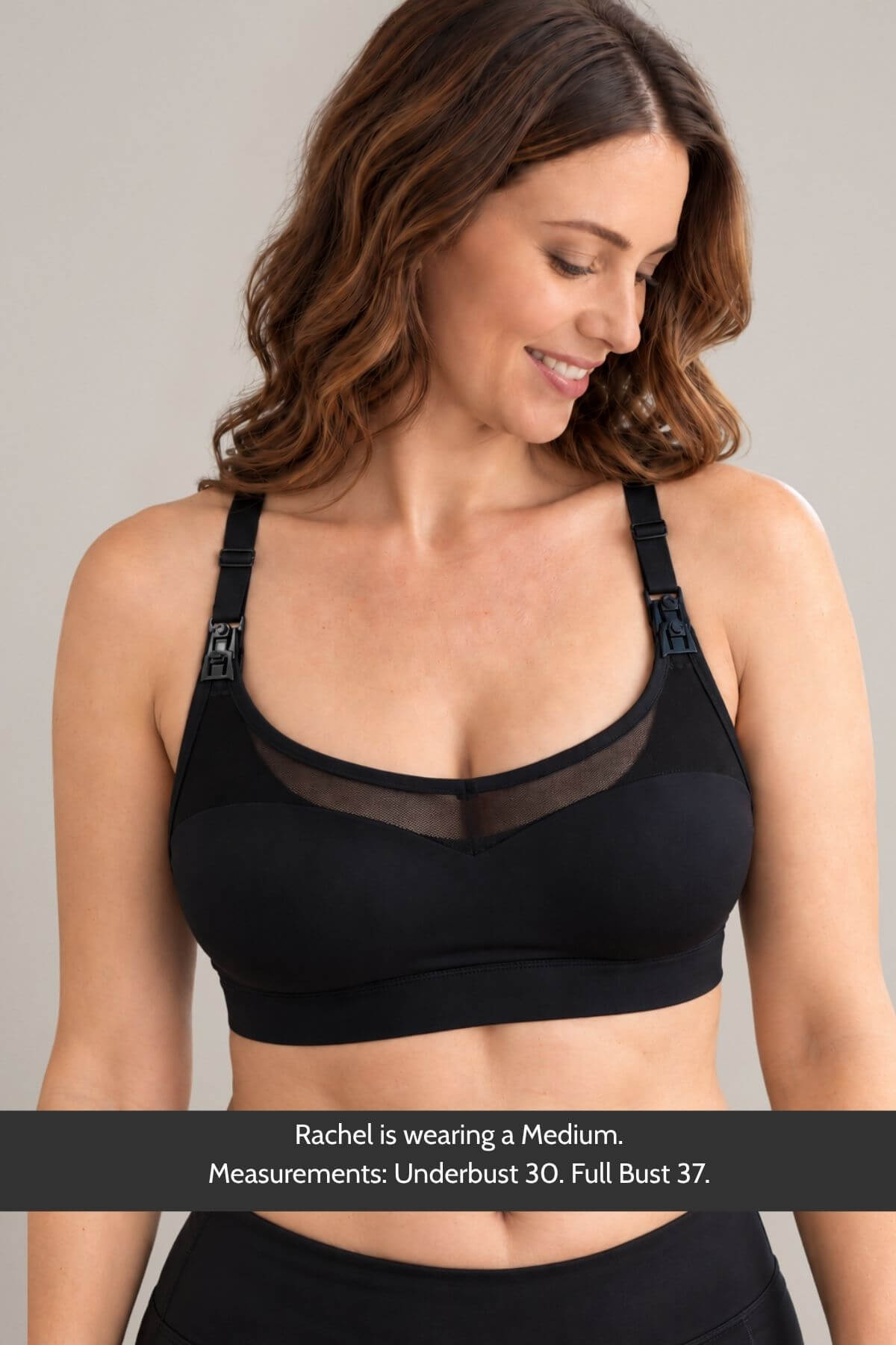A woman wearing the supermom sweetheart mesh racerback nursing &amp; hands-free pumping sports bra with a sheer mesh neckline shown from the chest up against a light gray studio background. A text banner at the bottom reads, &